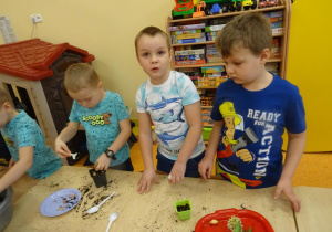 Dzieci sadzą cebulę w doniczkach.
